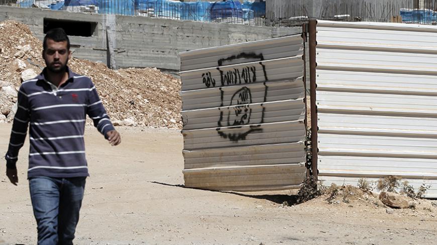 A Palestinian man walks past a graffiti portraying the Islamic State (IS) group's flag in the East Jerusalem neighbourhood of Beit Hanina on July 5, 2015. AFP PHOTO / AHMAD GHARABLI (Photo credit should read AHMAD GHARABLI/AFP/Getty Images)