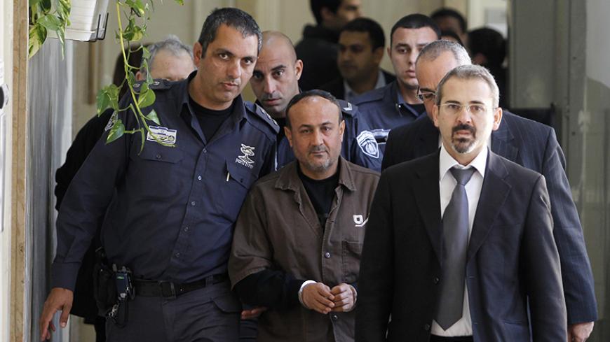 An Israeli prison guard (L) escorts jailed Fatah leader Marwan Barghouti (C) to a deliberation at Jerusalem Magistrate's court January 25, 2012. Convicted of murder for his role in attacks on Israelis, Barghouti was jailed for life by Israel in 2004. 
REUTERS/Baz Ratner (JERUSALEM - Tags: POLITICS CRIME LAW) - RTR2WTJR
