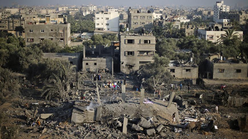 Palestinians survey a house which police said was destroyed in an Israeli air strikes in Gaza City July 8, 2014.  Israel launched an aerial offensive in the Gaza Strip on Tuesday, bombing more than 30 targets including homes and calling it part of a campaign named "Operation Protective Edge" targeting Hamas Islamist militants firing rockets at the Jewish state. The military urged Israelis within a 40-km (24-mile) radius of the southern coastal territory to stay within reach of protected areas and ordered su