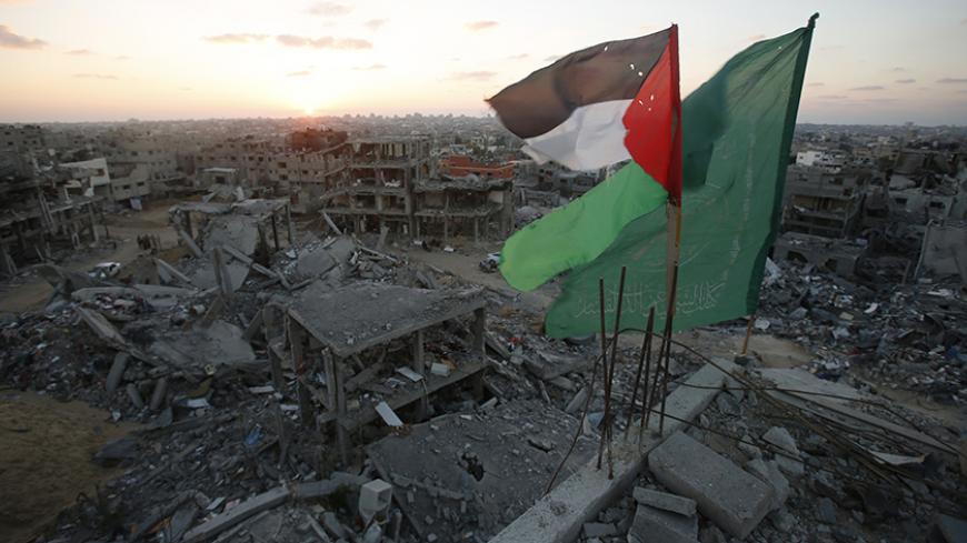 A Palestinian flag and a Hamas flag (R) flutter atop the wreckage of a house, which witnesses said was destroyed during the seven-week Israeli offensive, in the east of Gaza City September 3, 2014. Fifty days of war in one of the most densely populated parts of the world have left swathes of Gaza in ruins. With the economy reeling under an Israeli-Egyptian blockade, the enclave now faces an almost impossible task of rebuilding. Picture taken September 3, 2014.  REUTERS/Suhaib Salem (GAZA - Tags: CIVIL UNRES