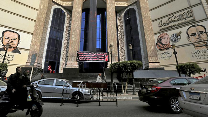 People and vehicles move past a black sign that reads "The press; It is not a crime" in front of the Egyptian Press Syndicate's headquarters in downtown Cairo, Egypt, November 20, 2016. REUTERS/Mohamed Abd El Ghany - RTSSGRD