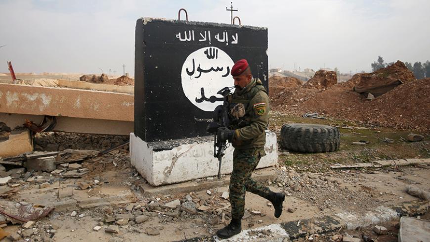 An Iraqi soldier walks next to a wall painted with the black flag commonly used by Islamic State militants, during a battle with Islamic State militants near Arabi neighborhood, north of Mosul, Iraq, January 21, 2017. REUTERS/Khalid al Mousily - RTSWOU6