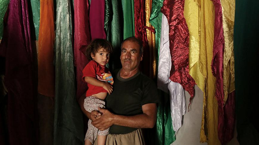 A Yazidi man carries his child at the Sharaf Al-Deen temple in Shingal's outskirts, Iraq, August 14, 2016.  REUTERS/Ari Jalal - RTX2KT69