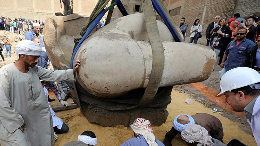Egyptian workers stand as a statue that might be of revered Pharaoh Ramses II, who ruled Egypt over 3,000 years ago, is raised, at the Matariya area in Cairo, Egypt, March 13, 2017. REUTERS/Mohamed Abd El Ghany - RTX30SBP