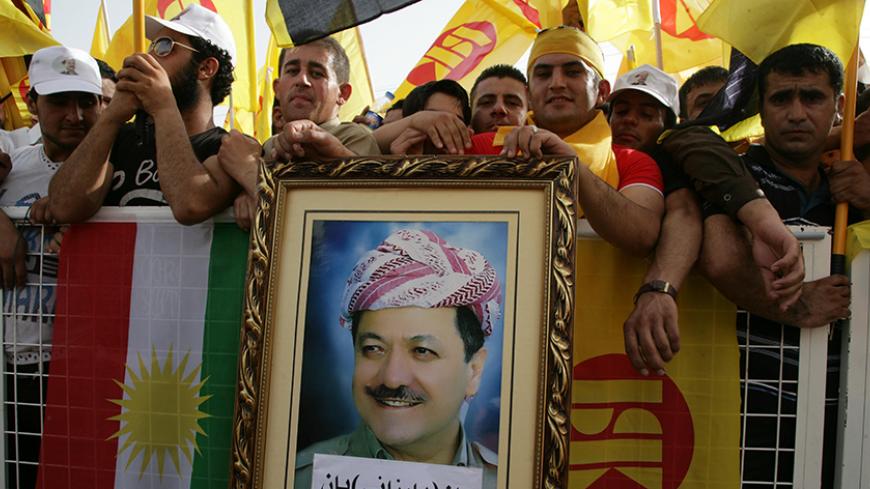 Massoud Barzani (portrait), the president of the Kurdish regional government in northern Iraq and leader of the Kurdistan Democratic Party, wave the party's flag (R) and the Kurdish flag (L) as he delivers a speech in the northern Iraqi Kurdish city of Arbil on May 26, 2013.  AFP PHOTO / SAFIN HAMED        (Photo credit should read SAFIN HAMED/AFP/Getty Images)