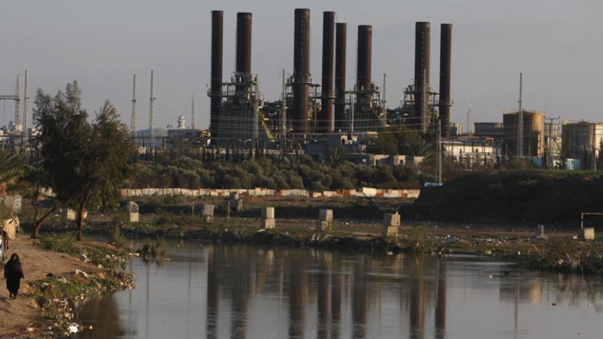 A Palestinian woman walks past Gaza's power station in the Gaza Strip March 15, 2014. The Gaza Strip's sole power station stopped generating electricity on Saturday, causing blackouts throughout the territory after it ran out of fuel, officials said. Gaza lacks much basic civil infrastructure and lives under an Egyptian-Israeli blockade meant to cut off arms flows but which also curbs imports of fuel and building supplies. REUTERS/Ibraheem Abu Mustafa (GAZA - Tags: POLITICS CIVIL UNREST ENERGY) - RTR3H86Y