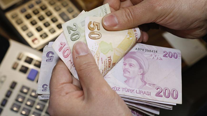 A money changer counts Turkish lira bills at a currency exchange office in Istanbul January 24, 2014. A global flight from emerging market assets gathered pace on Friday, sending the Turkish lira to a record low and setting global shares on course for their worst week this year. European shares fell, especially in firms exposed to emerging markets, and a sell-off on Wall Street was poised to extend into a second day as investors worried about the impact of slower growth in China, U.S. monetary policy and po