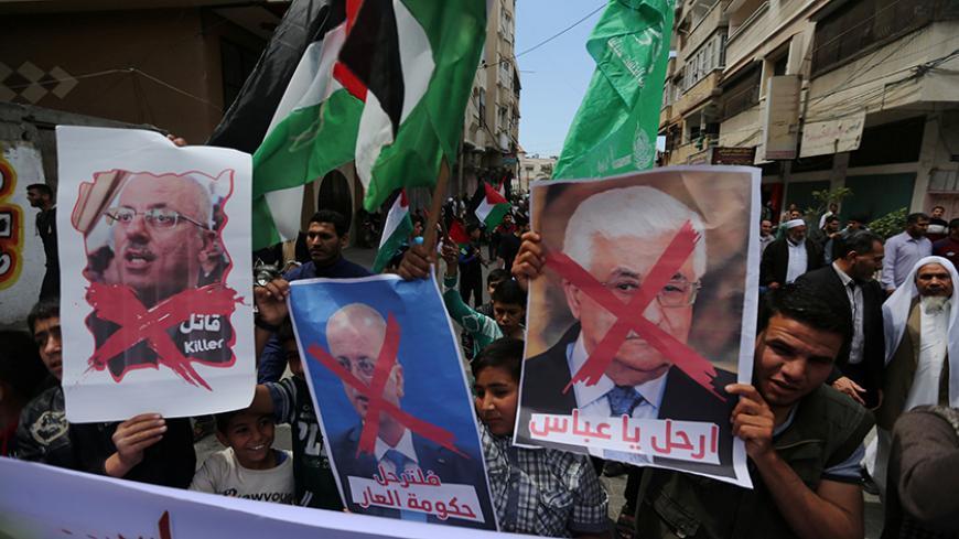 Hamas supporters hold crossed posters depicting Palestinian President Mahmoud Abbas and Palestinian Prime Minister Rami Hamdallah during a protest against them in Khan Younis in the southern Gaza Strip April 14, 2017. REUTERS/Ibraheem Abu Mustafa - RTX35JYQ