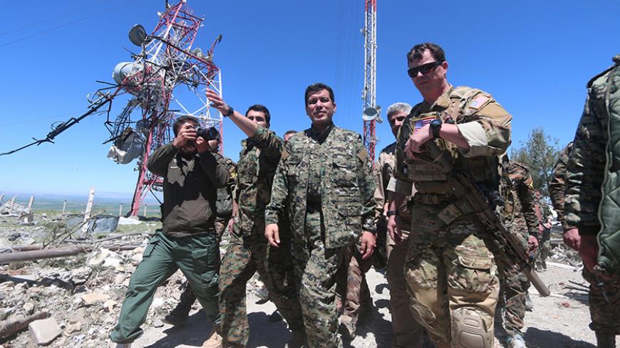 A U.S. military commander (R) walks with a commander (C) from the Kurdish People's Protection Units (YPG) as they inspect the damage at YPG headquarters after it was hit by Turkish airstrikes in Mount Karachok near Malikiya, Syria April 25, 2017. REUTERS/ Rodi Said - RTS13VA8