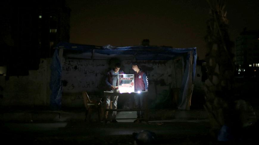 A Palestinian vendor uses battery-powered lights as he sells cigarettes during power cut at Shati refugee camp in Gaza City April 25, 2017. Picture taken April 25, 2017. REUTERS/Mohammed Salem TPX IMAGES OF THE DAY - RTS14598