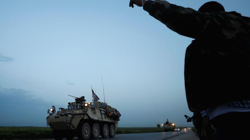 A Kurdish fighter from the People's Protection Units (YPG) gestures at a convoy of U.S military vehicles driving in the town of Darbasiya next to the Turkish border, Syria April 28, 2017. REUTERS/Rodi Said - RTS14EGQ