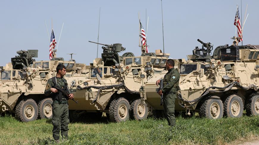 Kurdish fighters from the People's Protection Units (YPG) stand near U.S military vehicles in the town of Darbasiya next to the Turkish border, Syria April 29, 2017. Picture taken April 29, 2017. REUTERS/Rodi Said - RTS14IHP