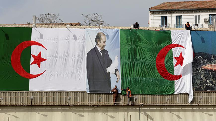 Algerian city employees install Algerian flags and President's Abdelaziz Bouteflika poster on the streets ahead of the Parliamentary election in Algiers, Algeria April 26,2017.Picture taken 26 April 2017. REUTERS/Ramzi Boudina - RTS14O6W