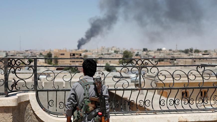 A Kurdish fighter from the People's Protection Units (YPG) looks at a smoke after an coalition airstrike in Raqqa, Syria June 16, 2017. REUTERS/Goran Tomasevic     TPX IMAGES OF THE DAY - RTS17E43
