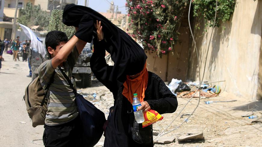 A displaced Iraqi woman removes her niqab, in western Mosul, Iraq, June 3, 2017. REUTERS/Alaa Al-Marjani - RTX38TUZ