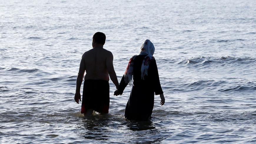 An Iranian couple walks in the sea in the Caspian Sea port city of Mahmoud Abad, in northern Mazandaran province on June 16, 2016.
/ AFP / ATTA KENARE (Photo credit should read ATTA KENARE/AFP/Getty Images)