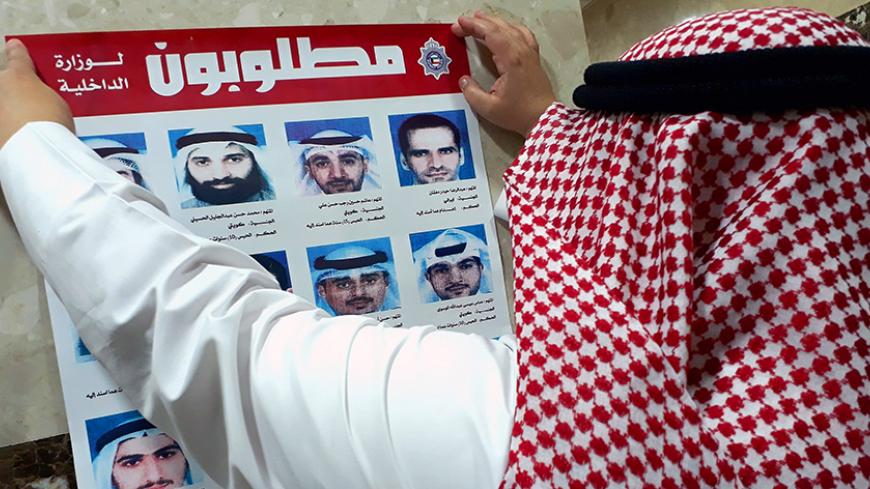 An official from Kuwait's interior ministry puts up a poster on July 20, 2017 in a Citizen Service Centre in Kuwait City, of fugitives convicted of belonging to a cell that had been formed and trained by Iran's Revolutionary Guards who were accused of plotting attacks in the state.
Kuwait expelled Iranian diplomats and closed some embassy missions after the emirate's top court convicted a "terror" cell of links to the Islamic republic, prompting Iran to threaten reciprocal measures. / AFP PHOTO / Yasser Al-