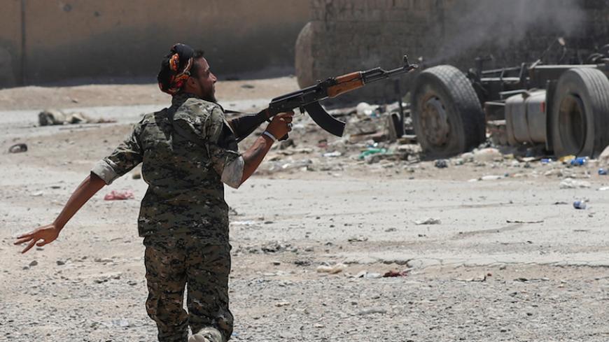 A Kurdish fighter from the People's Protection Units (YPG) fires his rifle at Islamic State militants as he runs across a street in Raqqa, Syria July 3, 2017. REUTERS/Goran Tomasevic TPX IMAGES OF THE DAY - RTS19M5W