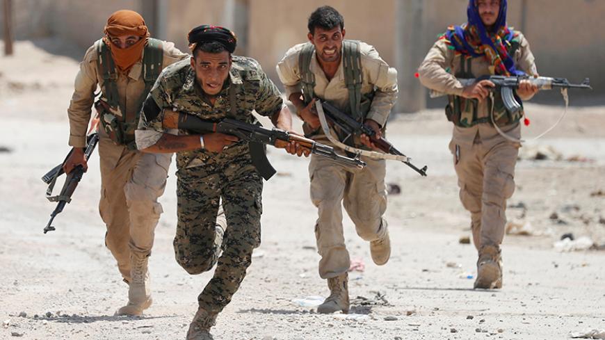 Kurdish fighters from the People's Protection Units (YPG) run across a street in Raqqa, Syria July 3, 2017. REUTERS/Goran Tomasevic TPX IMAGES OF THE DAY - RTS19M60