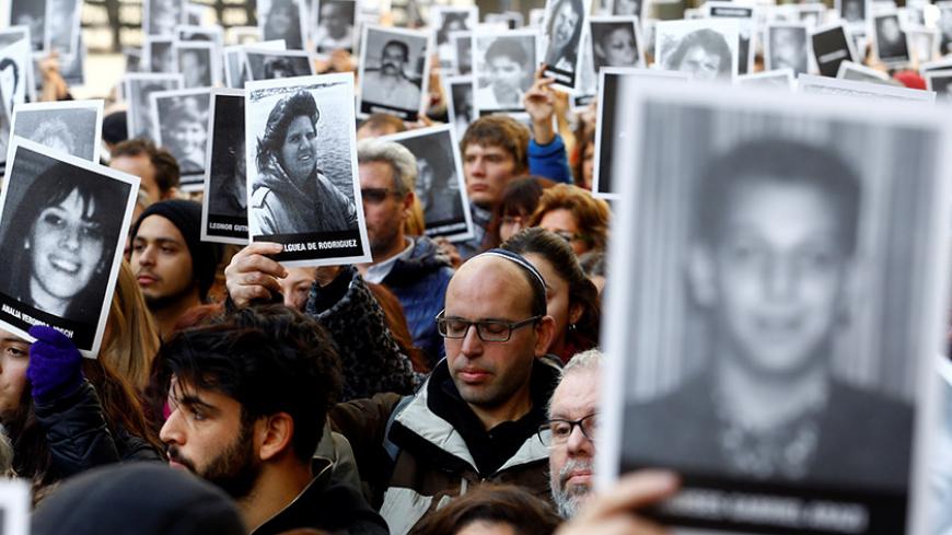 People hold up pictures of the victims of the AMIA Jewish center bombing during a ceremony to mark the 22nd anniversary of the 1994 attack that left 85 dead in Buenos Aires, Argentina, July 18, 2016. REUTERS/Enrique Marcarian  - RTSIJ2R