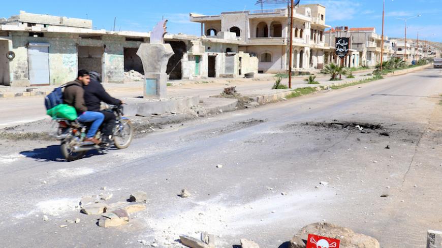 Men ride a motorbike past a hazard sign at a site hit by an airstrike on Tuesday in the town of Khan Sheikhoun in rebel-held Idlib, Syria April 5, 2017. The hazard sign reads, "Danger, unexploded ammunition". REUTERS/Ammar Abdullah - RTX3475J