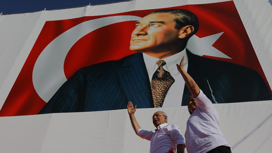 Kemal Kilicdaroglu, leader of main opposition Republican People's Party (CHP), and his wife Selvi greet people during a rally to mark the end of his 25-day long protest, dubbed "Justice March", against the detention of the party's lawmaker Enis Berberoglu, in Istanbul, Turkey July 9, 2017. A poster of modern Turkey's founder Ataturk is seen in the background. REUTERS/Huseyin Aldemir - RTX3AQZH