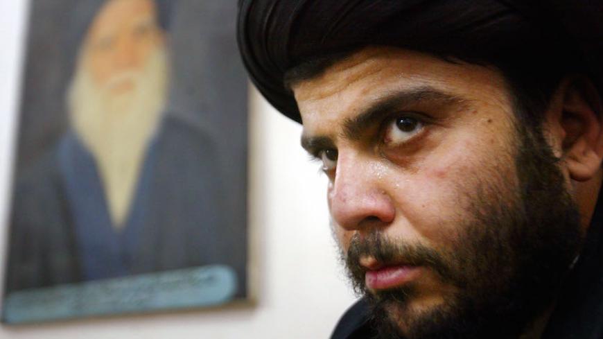 NAJAF, IRAQ - MAY 2:  Shiite cleric Sayed Moqtada al-Sadr sits in his offices beneath a portrait of his late father Ayatollah Mohammed Sadeq el-Sadr May 2, 2003 in Najaf, Iraq. A day earlier Iraqi Shiites gathered in the city to mark the anniversary of the death of Mohammed. (Photo by Mario Tama/Getty Images)      