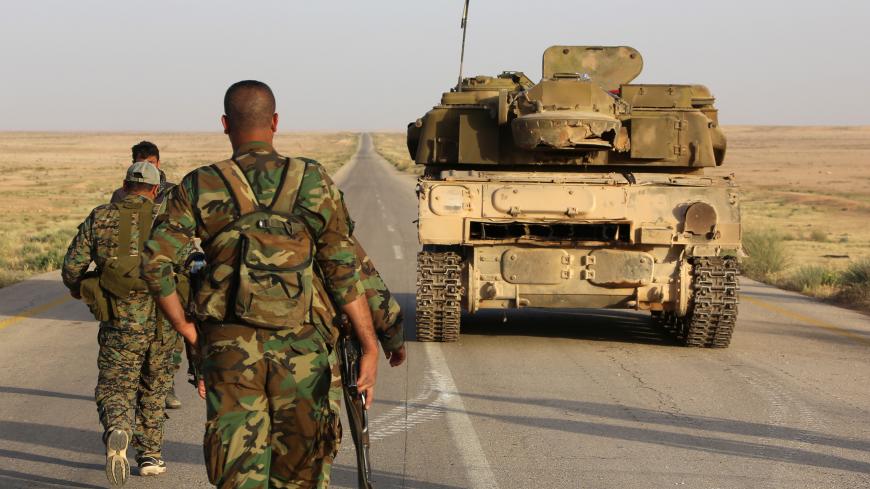 Syrian government forces secure a road for a military convoy in the desert area of Saba' Biyar, in southeastern Syria near the border with Iraq, on May 10, 2017, as fierce clashes are reported in the region. / AFP PHOTO / STRINGER        (Photo credit should read STRINGER/AFP/Getty Images)