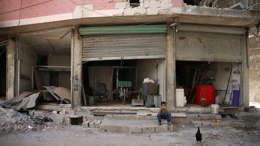A boy eats a corn as he sits in front of a shop in Ain Tarma, eastern Damascus suburb of Ghouta, Syria July 19, 2017. REUTERS/Bassam Khabieh - RTX3C32G
