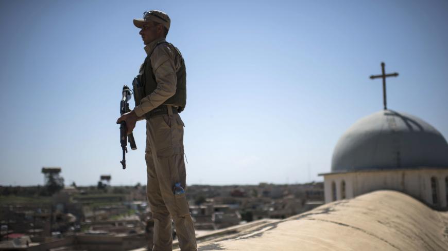 TOPSHOT - A Syriac Christian militiaman stands guard on top of a building during an easter ceremony at the Saint John's church (Mar Yohanna) in the nearly deserted predominantly Christian Iraqi town of Qaraqosh (also known as Hamdaniya), some 30 kilometres from Mosul, on April 16, 2017.
Qaraqosh was retaken by Iraqi forces late in 2016 as part of a massive offensive to wrest back the nearby city of Mosul from Islamic State (IS) group fighters but it remains almost completely deserted.
/ AFP PHOTO / CHRIST