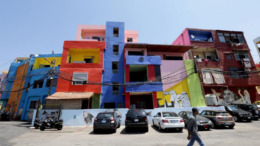 A man walks past houses, painted as part of the "Ouzville" project, in Beirut's southern Ouzai neighbourhood, on August 19, 2017.
Starting 18 months ago, Nasser began implementing a plan to invite international and local artists to beautify parts of Beirut with street art, and Ouzai in particular, by painting walls in brilliant blues, reds, yellows and greens, and adorning others with enormous murals, doodles, and cartoon characters. / AFP PHOTO / ANWAR AMRO (Photo credit should read ANWAR AMRO/AFP/G