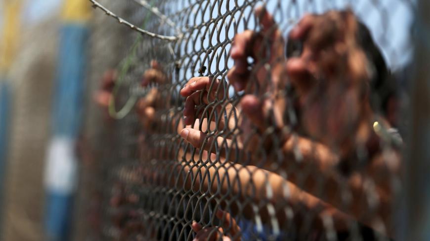 Palestinians gather in front of the gate of Rafah border crossing between Egypt and Gaza during a protest against the blockade calling for reopening of the crossing, in the southern Gaza Strip July 3, 2017. REUTERS/Ibraheem Abu Mustafa - RC15A4BE0430