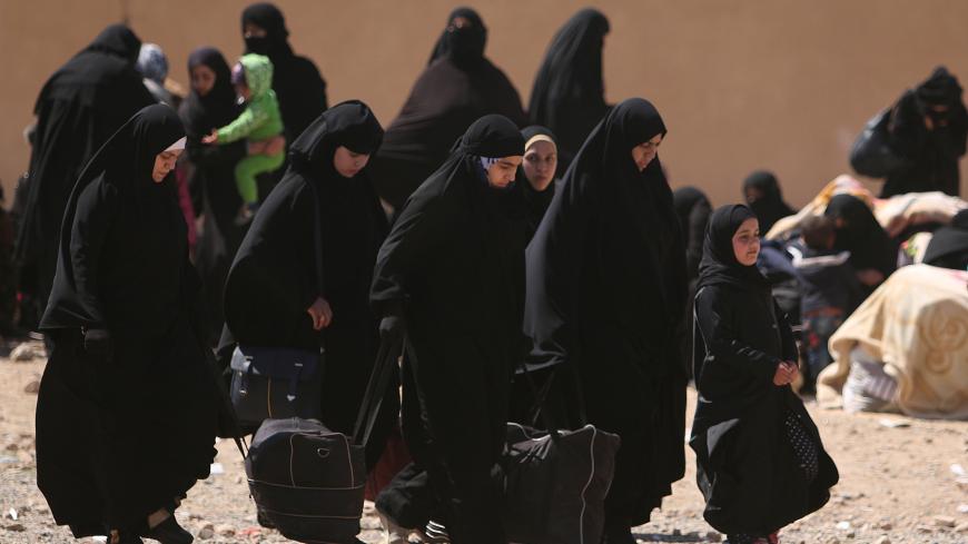 Women, who fled from Raqqa city, carry their belongings in al-Mahmudli village, west of Raqqa, Syria April 5, 2017. REUTERS/Rodi Said - RC1293527DB0