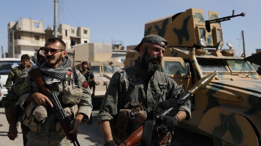 A fighter of the Syrian Democratic Forces (SDF) carries a weapon as he stands near a military vehicle in Raqqa, Syria, October 16, 2017. REUTERS/Rodi Said - RC1A33A0C9A0