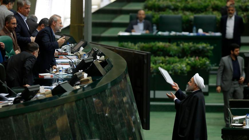 Iran's President Hassan Rouhani (R) hands out documents to Parliament Speaker Ali Larijani after presenting his budget for 2018-2019 on December 10, 2017, in Tehran. / AFP PHOTO / ATTA KENARE        (Photo credit should read ATTA KENARE/AFP/Getty Images)