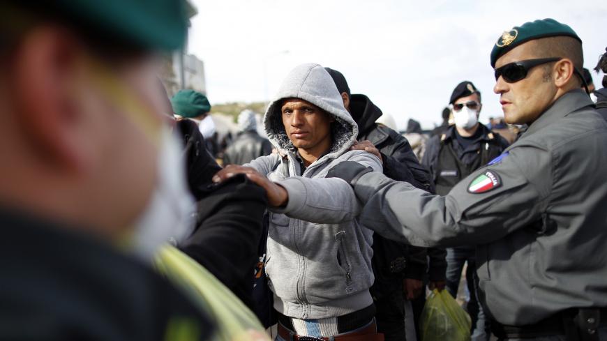 People fleeing unrest in Tunisia are escorted by Guardia di Finanza police officers as they arrive at the southern Italian island of Lampedusa March 30, 2011. The International Organisation for Migration estimates a million people have flooded out of Libya alone since the uprisings began. The vast majority - about 98 percent - have ended up in neighbouring states like Egypt, Tunisia or Algeria. But coupled with the thousands of Tunisians who have taken advantage of looser security following the fall of pres