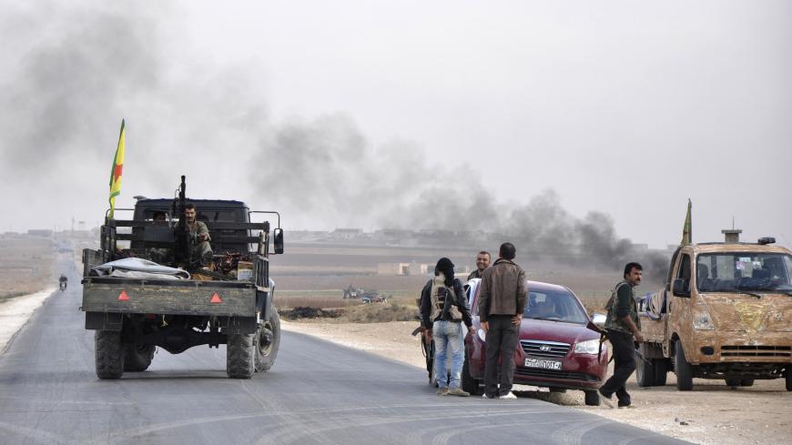 A member of the Kurdish People's Protection Units (YPG) mans a weapon mounted on a pick-up truck as others talk to each others along a street in the west of the city of Ras al-Ain, after capturing it from Islamist rebels November 5, 2013. Redur Xelil, spokesman for the armed wing of the Syrian Kurdish Democratic Union Party (PYD), said Kurdish militias had seized the city of Ras al-Ain and all its surrounding villages. Syrian Kurdish fighters have captured more territory from Islamist rebels in northeastern