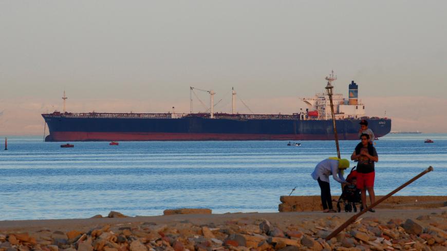 People walk on the beach as a container ship crosses the Gulf of Suez towards the Red Sea before entering the Suez Canal, in El Ain El Sokhna in Suez, east of Cairo, Egypt April 24, 2017. Picture taken April 24, 2017. REUTERS/Amr Abdallah Dalsh - RC1E42014B40