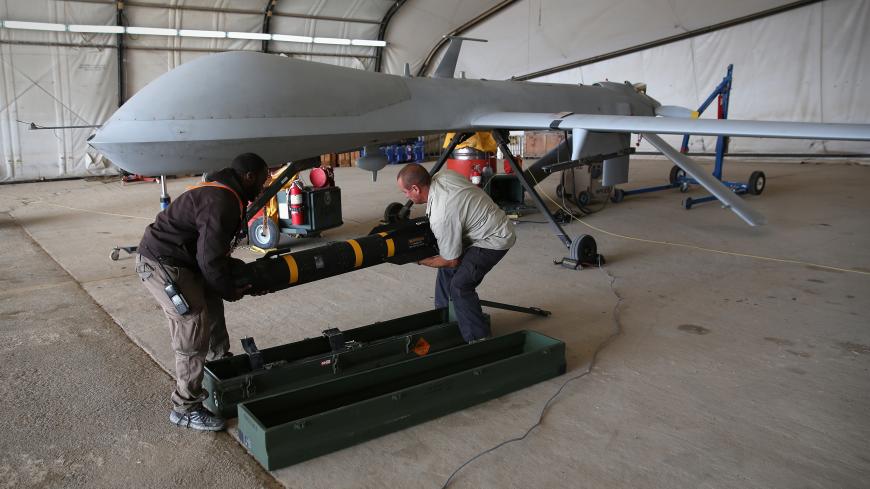 UNSPECIFIED, UNSPECIFIED - JANUARY 07: Contract workers load a Hellfire missile onto a U.S. Air Force MQ-1B Predator unmanned aerial vehicle (UAV), at a secret air base in the Persian Gulf region on January 7, 2016. The U.S. military and coalition forces use the base, located in an undisclosed location, to launch drone airstrikes against ISIL in Iraq and Syria, as well as to distribute cargo and transport troops supporting Operation Inherent Resolve. The Predators at the base are operated and maintained by