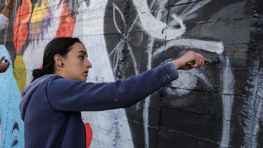 Suha Sultan, a 20-year-old graffiti artist and student, uses a brush to draw a mural on a wall in the Jordanian capital Amman on December 16, 2017.
A tiny group of graffiti artists are on a mission -- daubing flowers, faces and patterns across the capital Amman to bring more colour to the lives of its four million inhabitants.
In a conservative society like Jordan's, the graffiti artists have constantly had to challenge convention to carve out a niche for their works, though still with limits as they steer 