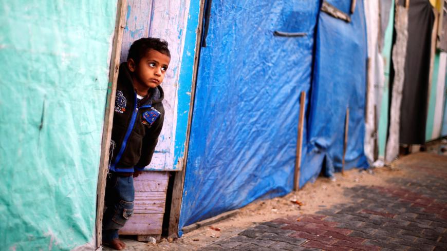 A Palestinian boy who lives in a container as a temporary replacement for his house that was destroyed in the 2014 war, looks out on a rainy day in Beit Hanoun in the northern Gaza Strip December 15, 2016. REUTERS/Suhaib Salem - RC1DAD9F6BE0