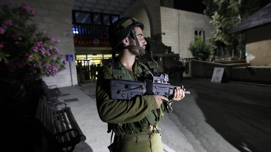 An Israeli soldier guards one of the entrances of Bir Zeit University near Ramallah during an operation in search for members of Islamist Hamas movement's on June 19, 2014. Israeli troops arrested some 30 Palestinians in the West Bank overnight as they ramped up a massive search for three teenagers believed kidnapped by Hamas, the army said.  AFP PHOTO/ ABBAS MOMANI        (Photo credit should read ABBAS MOMANI/AFP/Getty Images)