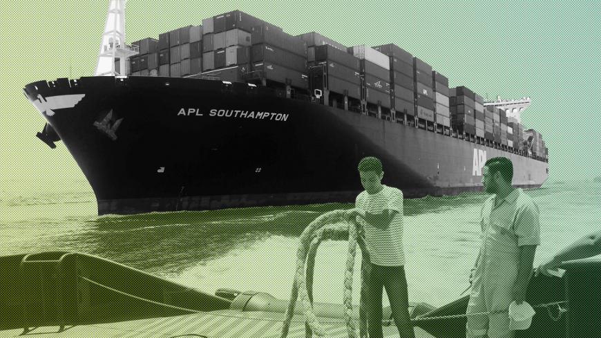 Employees work on a boat in front of a container ship, as they are both crossing the new waterway of the Suez canal on July 25, 2015, in the Egyptian port city of Ismailia, east of Cairo. Egypt began the first trial run of its "new Suez canal," officials and state media said, ahead of the formal inauguration of the new shipping route on August 6. Dubbed the Suez Canal Axis, the new 72-kilometre (45 mile) project is aimed at speeding up traffic along the existing waterway by reducing the waiting period of ve