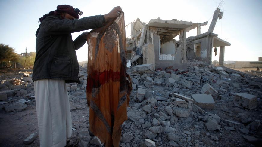 A Houthi militant holds a blood-stained garment at the site of a Saudi-led air strike, north of Yemen's capital Sanaa, March 8, 2018. REUTERS/Mohamed al-Sayaghi - RC1D17254740