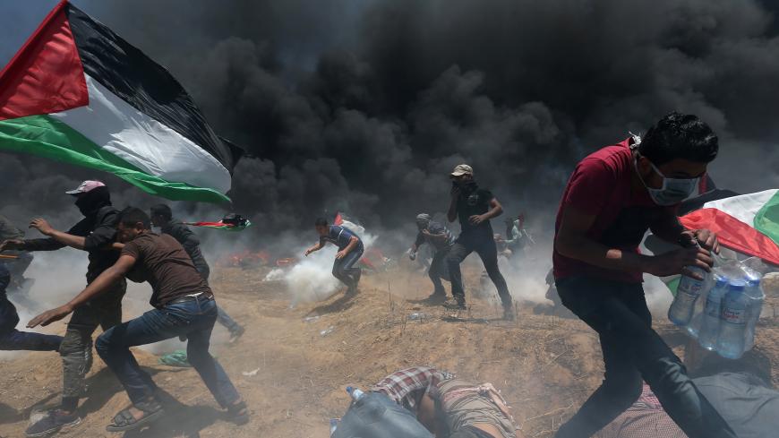 Palestinian demonstrators run for cover from Israeli fire and tear gas during a protest against U.S. embassy move to Jerusalem and ahead of the 70th anniversary of Nakba, at the Israel-Gaza border in the southern Gaza Strip May 14, 2018. REUTERS/Ibraheem Abu Mustafa - RC1712A20510