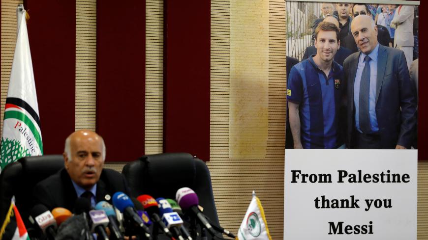 A poster of Palestinian FA chief Jibril Rajoub with Argentina's soccer player Lionel Messi is seen during Rajoub's news conference, in Ramallah in the occupied West Bank June 6, 2018. REUTERS/Mohamad Torokman - RC13B03D01D0