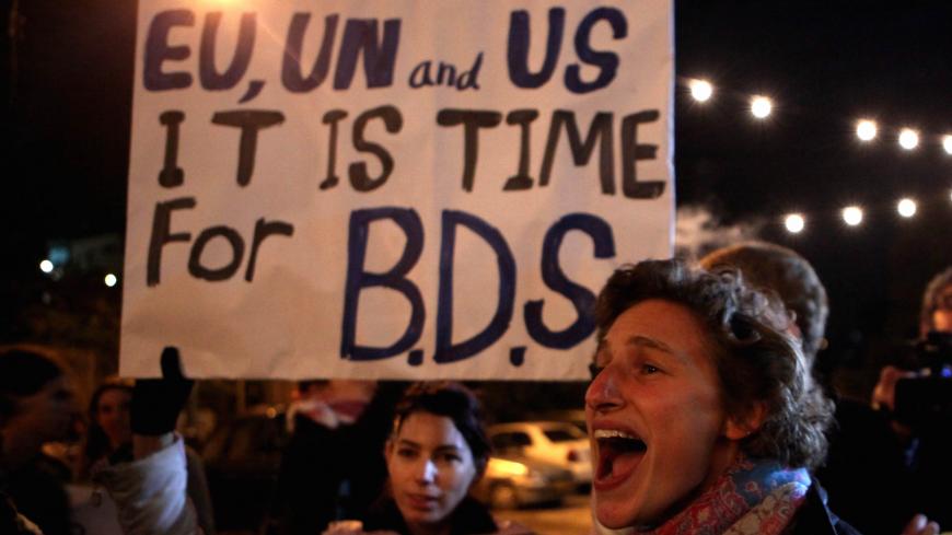 Demonstrators hold a placard urging the international community to take action against Israel's settlement policy in the occupied territories as left-wing Israeli and foreign peace activists join Palestinians in a protest in the Arab east Jerusalem neighborhood of Sheikh Jarrah on November 04, 2009. According to Israeli radio, about 200 people protestested in Sheikh Jarrah against what they call the "Judaisation" of Arab east Jerusalem and the ongoing construction of Jewish settlements in the Jerusalem area