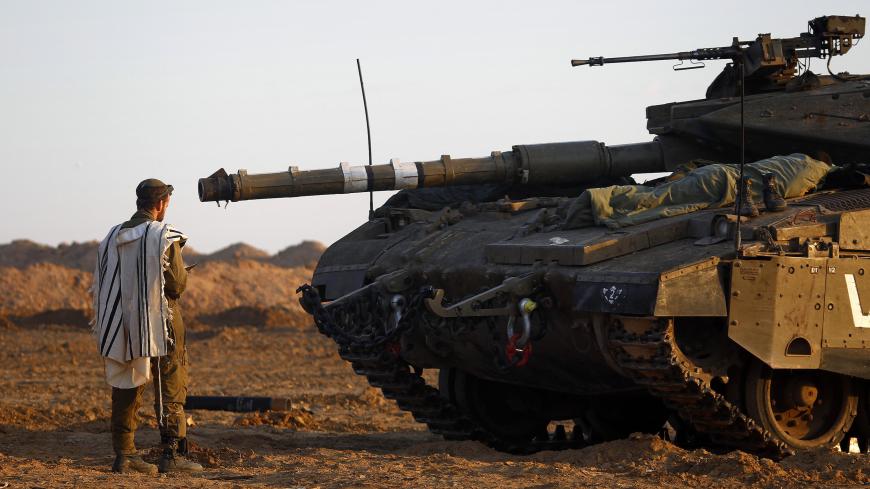 An Israeli soldier prays by a tank at an Israeli Defence Forces (IDF) staging area in the central Gaza border November 21, 2012.  Israeli air strikes shook the Gaza Strip and Palestinian rockets struck across the border as U.S. Secretary of State Hillary Clinton held talks in Jerusalem in the early hours of Wednesday, seeking a truce that can hold back Israel's ground troops.  REUTERS/Yannis Behrakis (ISRAEL - Tags: CONFLICT CIVIL UNREST MILITARY RELIGION) - GM1E8BL143K01