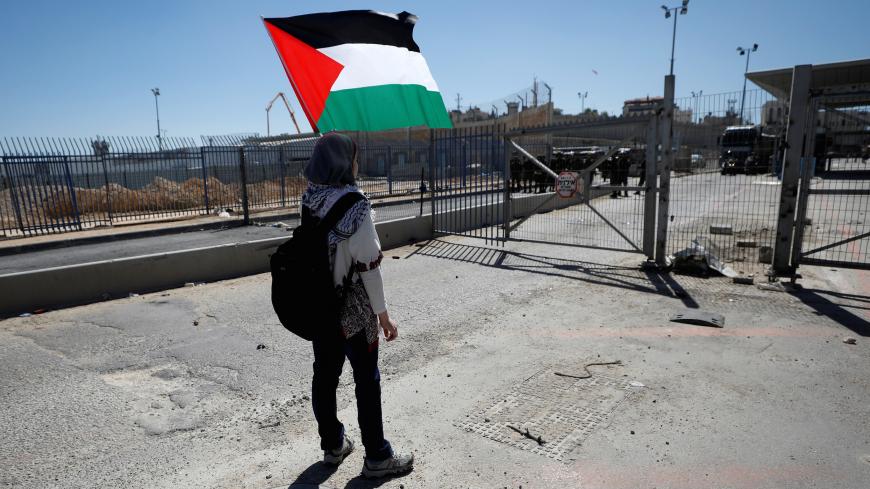 A girl holds a Palestinian flag in front of Israeli troops during clashes at a protest against U.S. President Donald Trump's decision on Jerusalem ahead of International Women's Day, in Ramallah, in the occupied West Bank March 7, 2018. REUTERS/Mohamad Torokman - RC1596807590