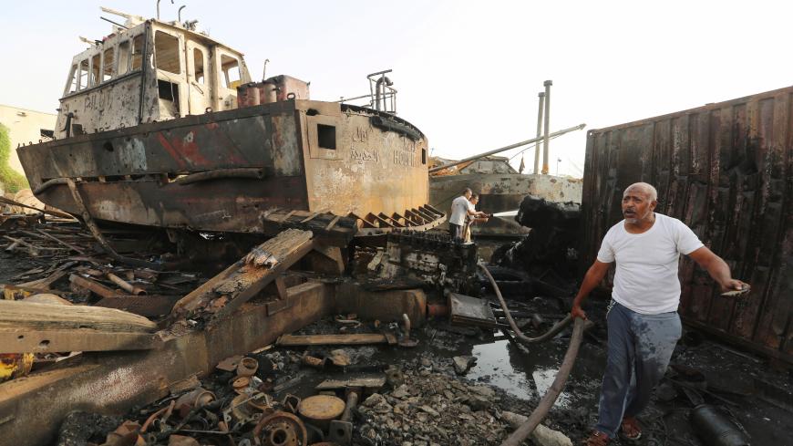 Workers inspect damage at the site of an air strike on the maintenance hub at the Hodeida port, Yemen May 27, 2018. REUTERS/Abduljabbar Zeyad - RC1CB0640040